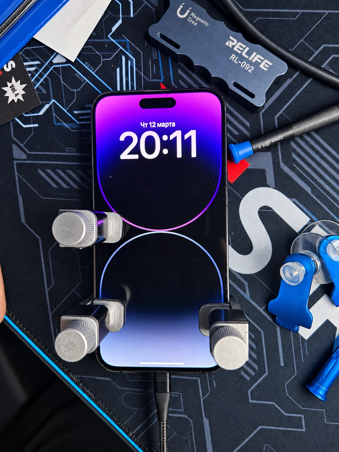iPhone mit eingeschaltetem Display auf dem Reparaturplatz