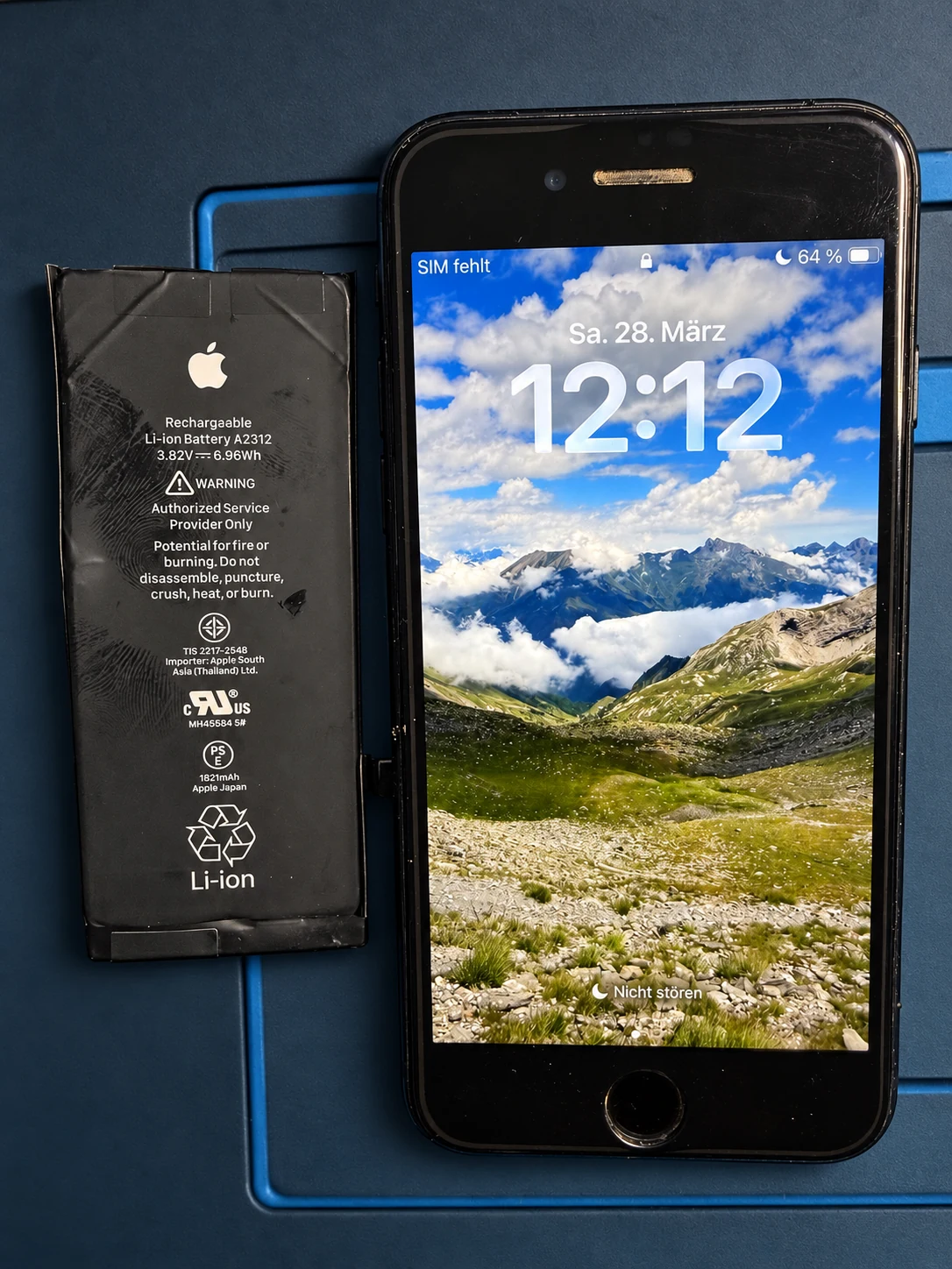 Smartphone und Ersatzakku auf der Reparaturmatte